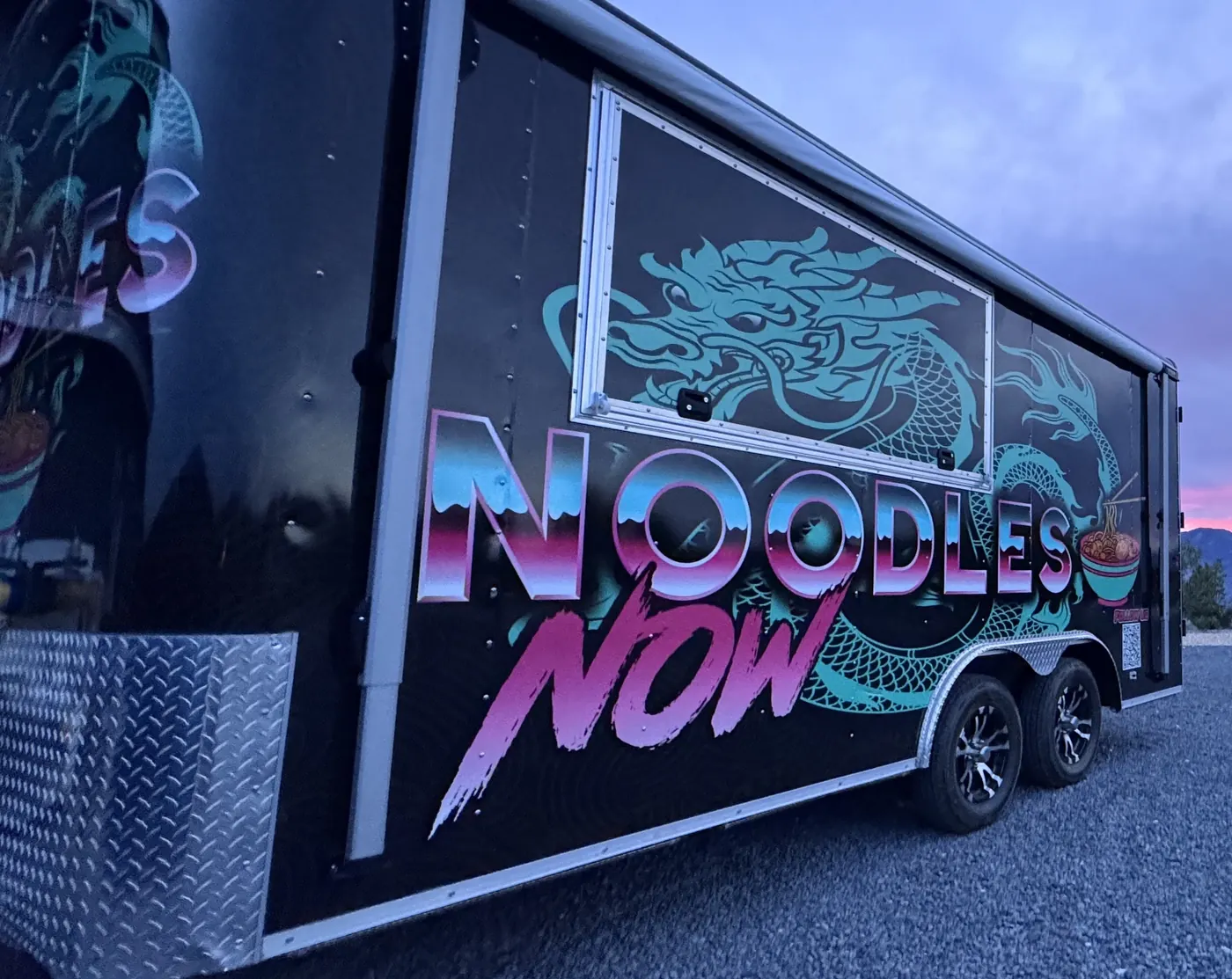 The Noodles Now trailer at dusk under a purple and pink sky